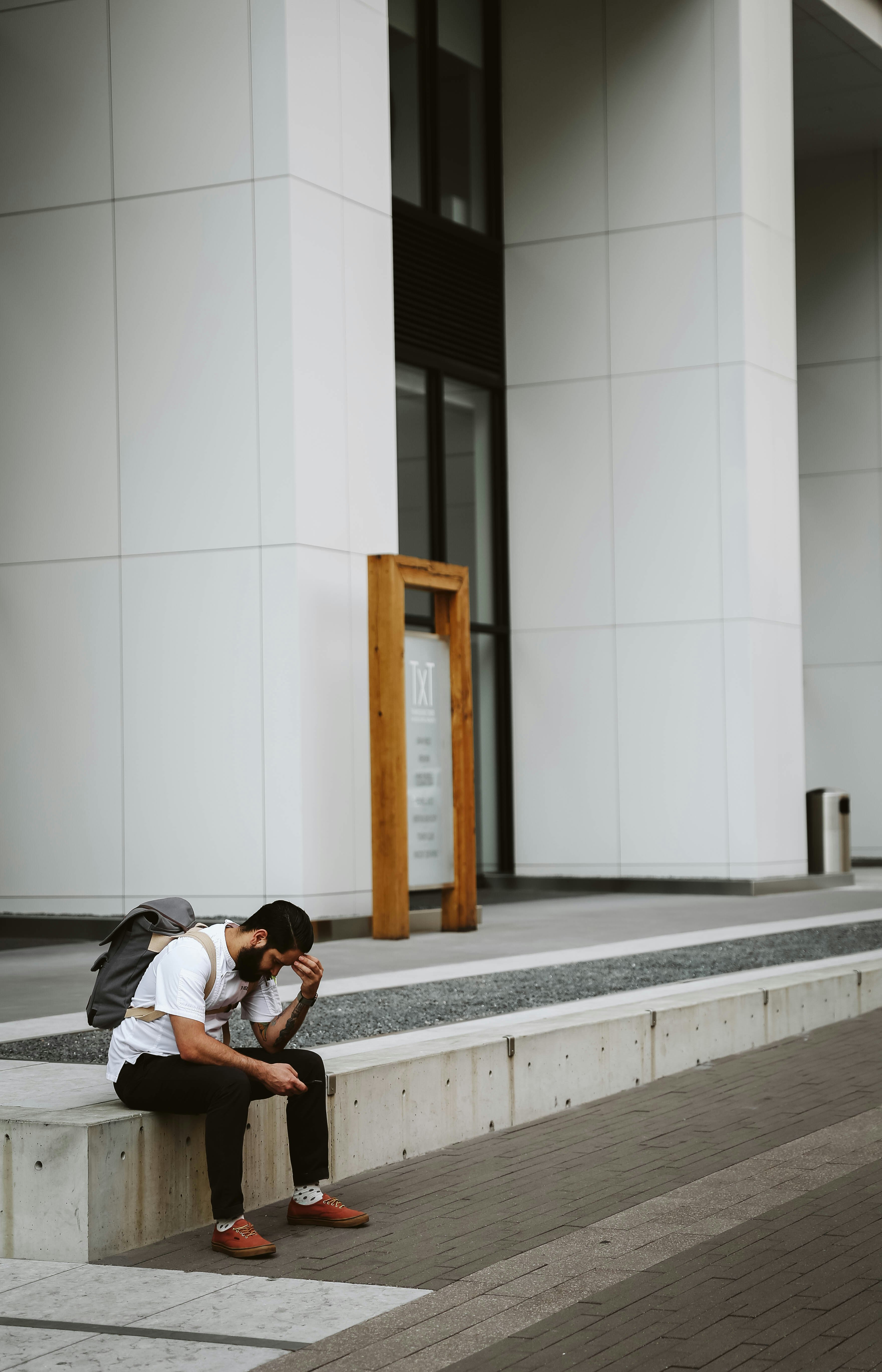 man in white shirt and black pants sitting outdoors